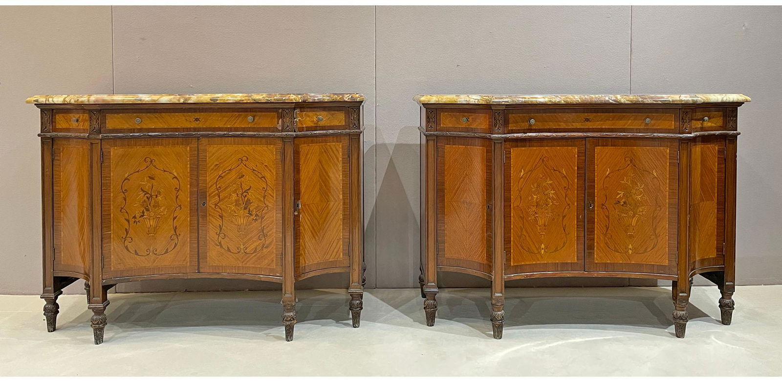 Pair of Louis XVI Style Kingwood Credenzas: This pair of kingwood credenzas have shaped Perlato Royal molded marble tops, above a pair of concave center doors and a short frieze drawer, each with cross-banding panels and inlaid foliate decorati