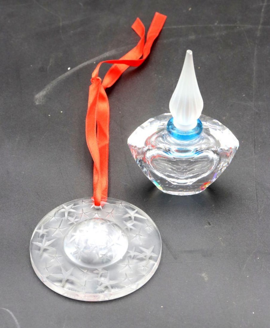 Pair of Lalique and Swarovski Crystal Trinkets: Pair of Lalique and Swarovski Crystal Trinkets. A Lalique star-carved glass medallion measuring approx. - 3" dia. Also includes a Swarovsky perfume bottle measuring approx. - 4" H x 3" W. 