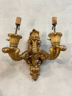 2 Light Electrified Giltwood Sconce: A 2 light electrified giltwood sconce featuring scrollwork throughout. Do show moderate wear along with a few cracks and a repair has been made to the center section. It measures approx 14? h x 14? w