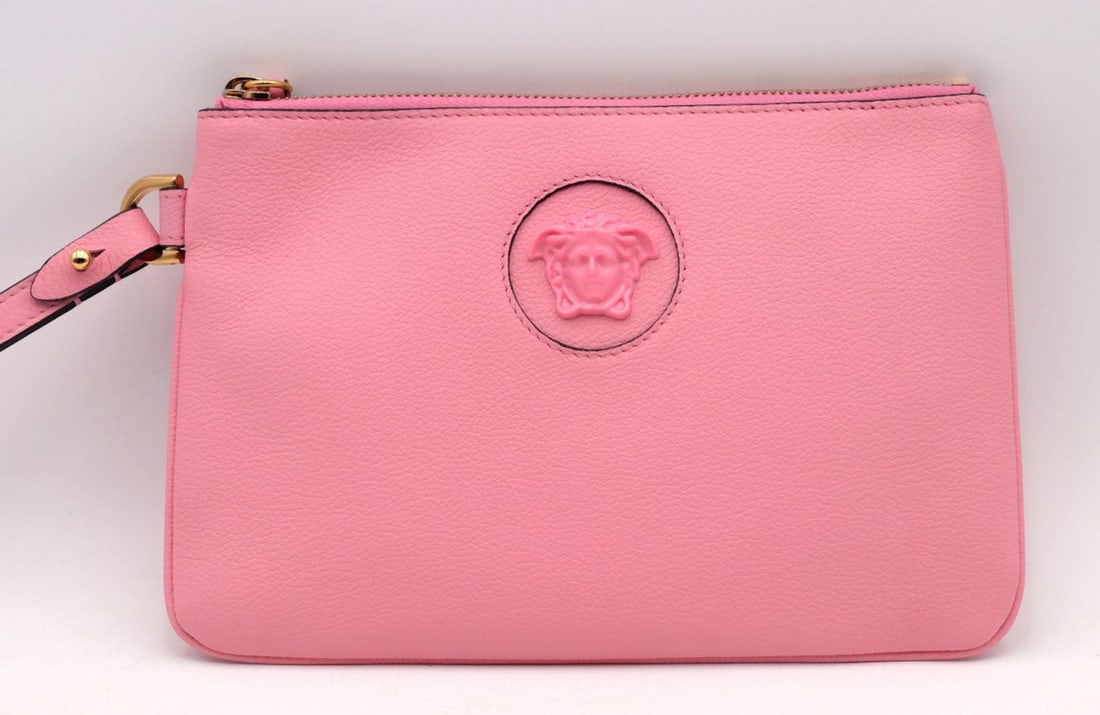 Versace Baby Pink Medusa Pouch Vitello: VERSACE Baby Pink Medusa Vitello Pouch Crafted in smooth baby pink Vitello leather, this elegant pouch is adorned with Versace’s iconic Medusa emblem in monochrome hardware—an instantly re