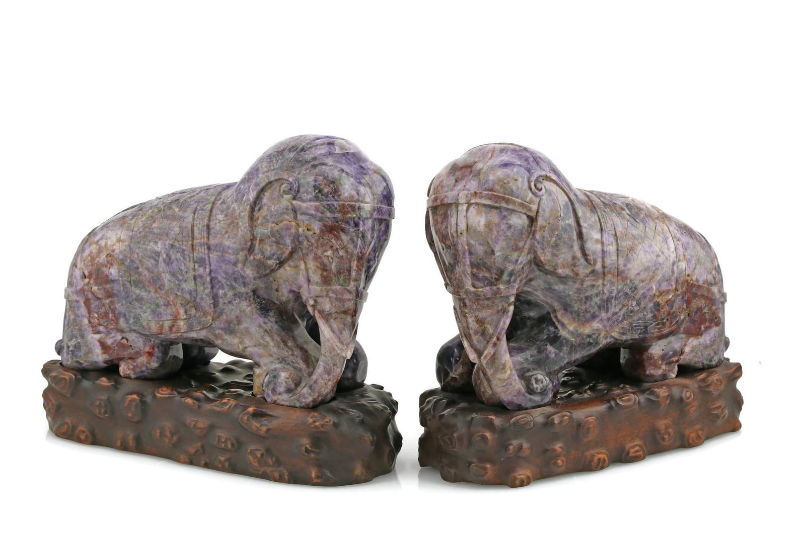 Pair of Carved Amethyst Elephants: Pair of Amethyst Elephant Figures on Wooden Bases 20th Century 8" H x 9.5" L x 4" W A pair of carved amethyst elephant figures, each modeled in a seated pose and mounted on fitted wooden