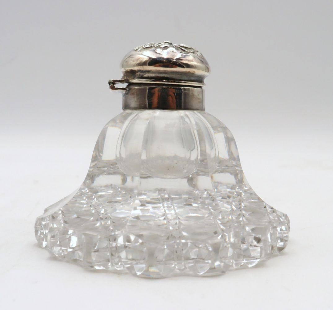 Early 20th C. Cut Crystal & Sterling Silver Inkwell: Early 20th Century Cut Crystal & Sterling Silver Inkwell 3" H x 4 1/4" Dia. A cut crystal inkwell fitted with a sterling silver hinged lid, featuring a faceted body and circular form. The 