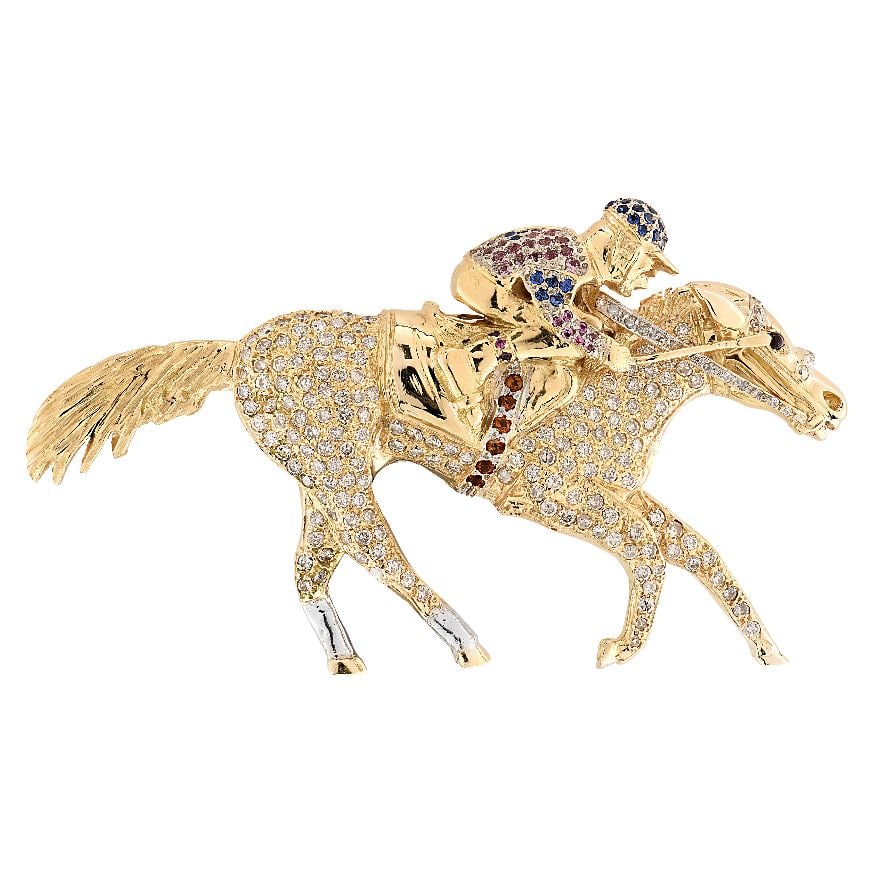 Diamond & Sapphire Jockey & Horse Brooch: Diamond & Sapphire Jockey & Horse Brooch Off to the races with this delightfully spirited brooch, exquisitely crafted in 18 karat yellow and white gold and capturing a lively jockey in full st