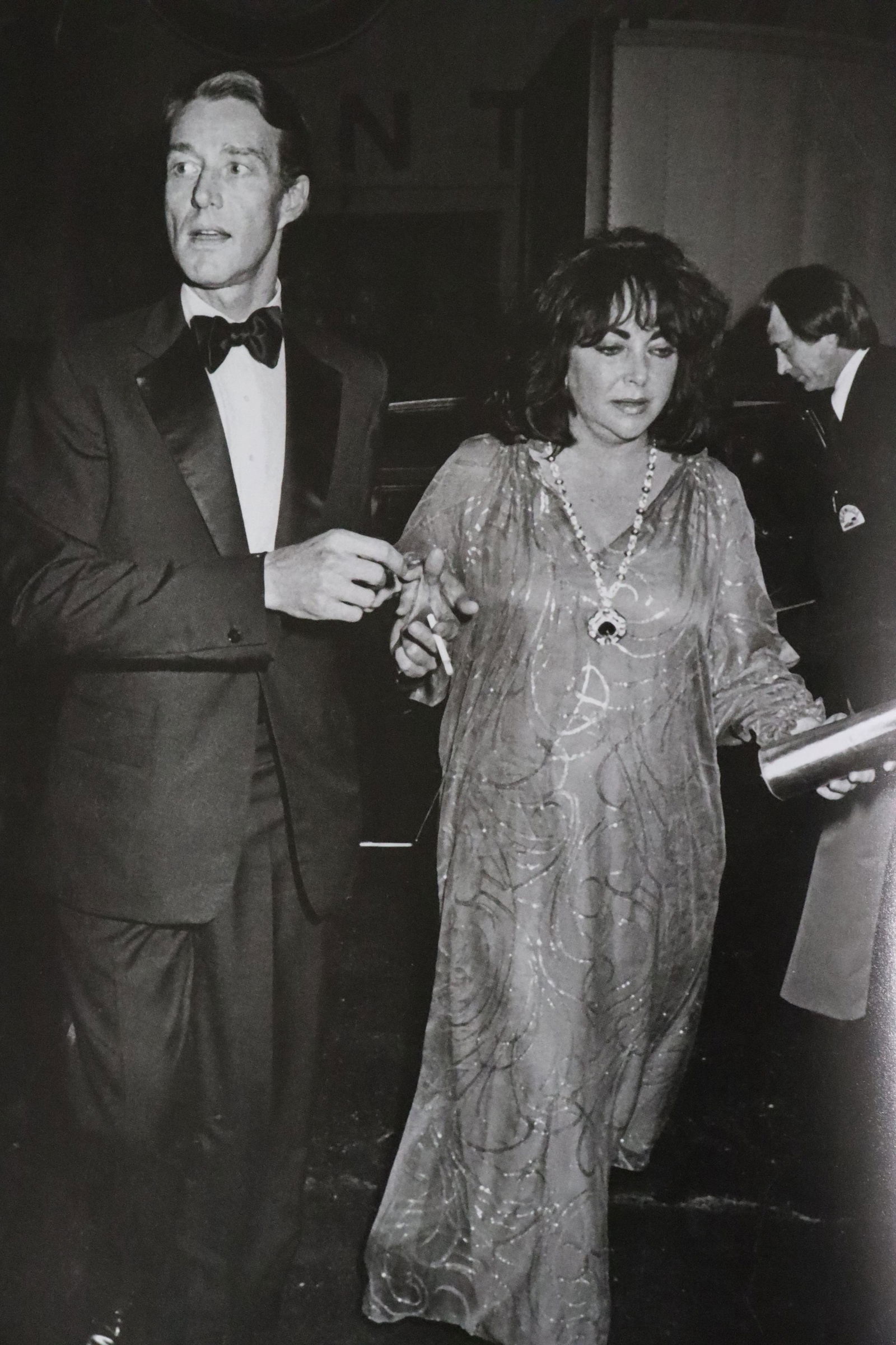 Halston escorts Liz Taylor, Studio 54, Photo-Litho: UNKNOWN PHOTOGRAPHER Halston escorts Liz Taylor into the club, Studio 54 Photo-Litho Printed circa late 20th century 13 5/8" x 9" (Image Size)