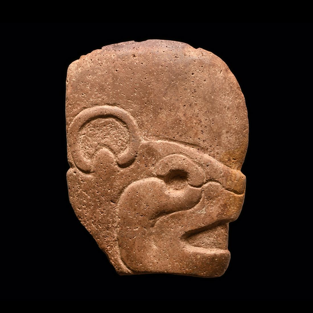 A Mayan Jaguar Head Hacha, Classic Maya Period, ca. 600 - 900 CE: A Mayan Jaguar Head Hacha, Classic Maya Period, ca. 600 - 900 CE, ca. 600 - 900 CE: Medium: Stone The pinkish-tan hardstone hacha carved in low relief depicting a jaguar's head having large rounded ea