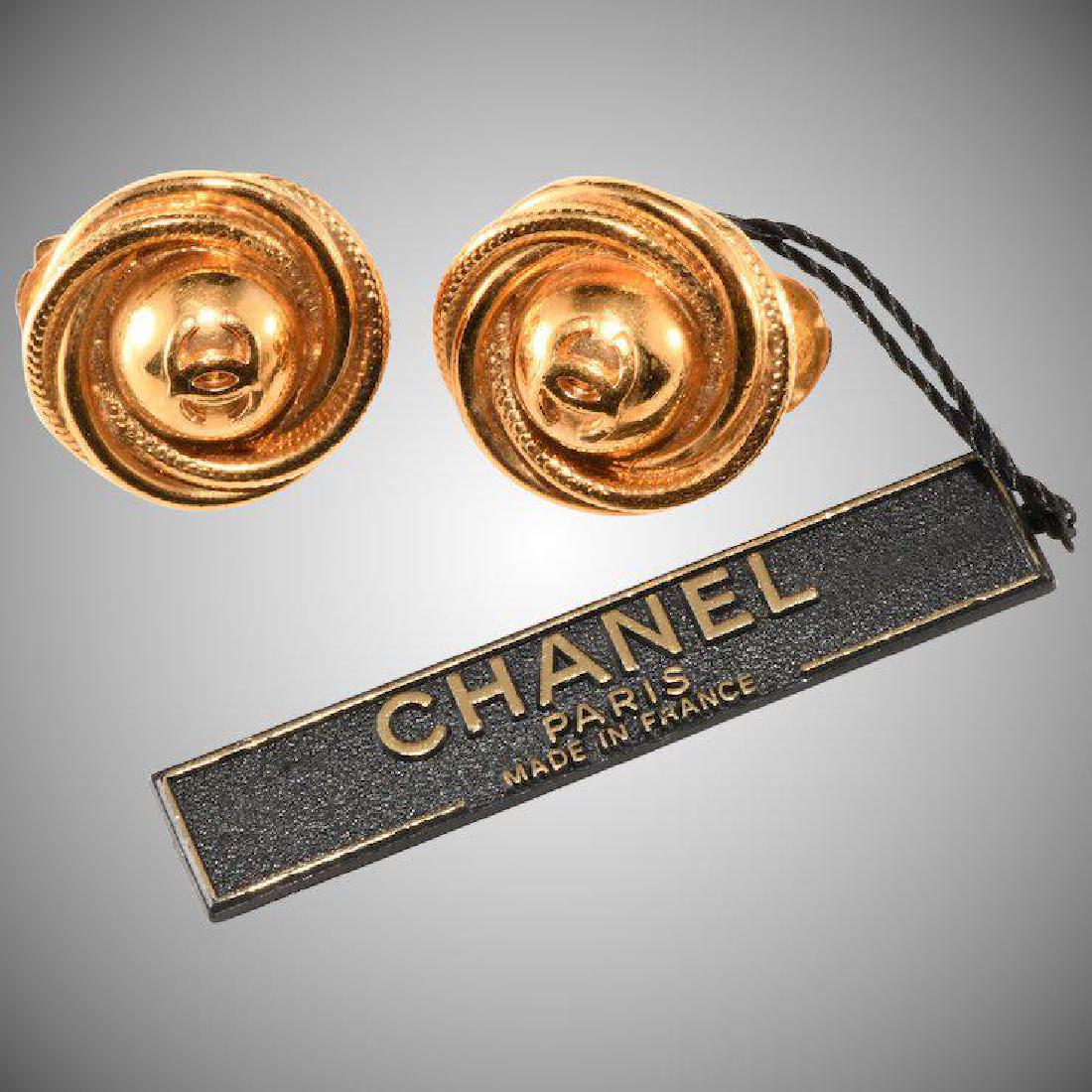 Chanel CC Logo Earrings With Original Tag: Brand: Chanel Description: Swirling clip back earrings with Chanel CC logo crafted of gold plated metal. Hallmark: made in France in 1997 for the fall season. .75" across Condition: Vintage/very good