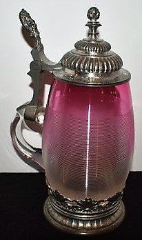 Pink/Cranberry Threaded Glass Beer Stein: Pink to Clear Threaded Glass Beer Stein, has inscription around the lid 1908. Has metal ring base. Measures 8.5"