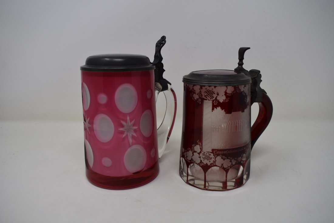 Pair of Glass Beer Steins Ruby/Pink Glass: A pair of glass beer steins pink to white overlay with pewter lid, and ruby etched with glass inlay. Both are 1/2 liter