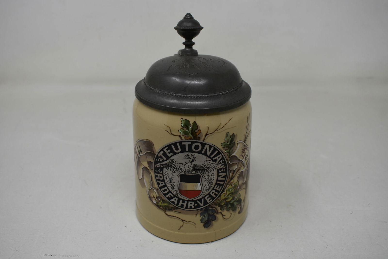 Mettlach Teutonia Radfahr Bicycling Club Beer Stein #1526: Mettlach #1526 Teutonia Radfahr Bicycling Club 1/2 liter Pug Beer Stein. Body has a hairline, #10 on the thumblift, pewter lid is initialed. Otherwise in mint condition.