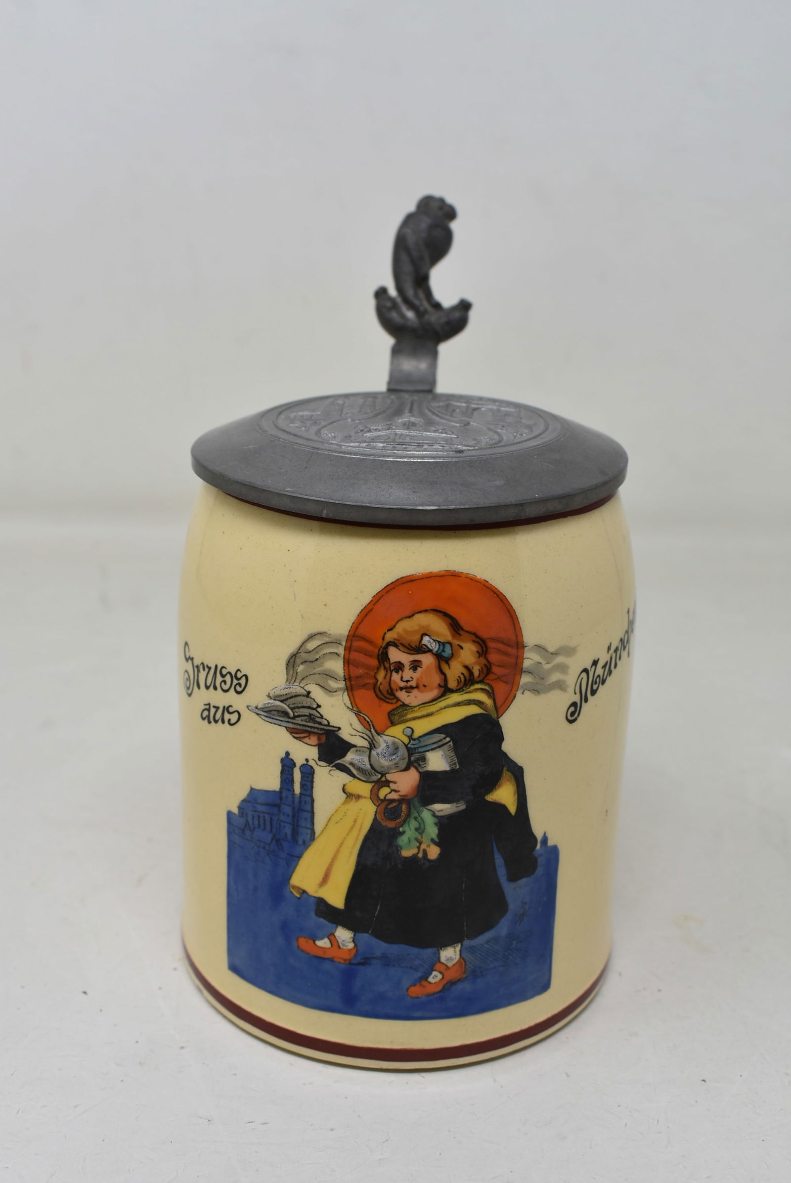 1/2 Liter Porcelain Beer Stein with Pewter Lid Münchner Kindl Girl: 1/2 Liter Porcelain Beer Stein with Pewter Lid, München Kindl Girl. Strap is loose, Chip on the rim, non-visible, with tight hairline on right side.