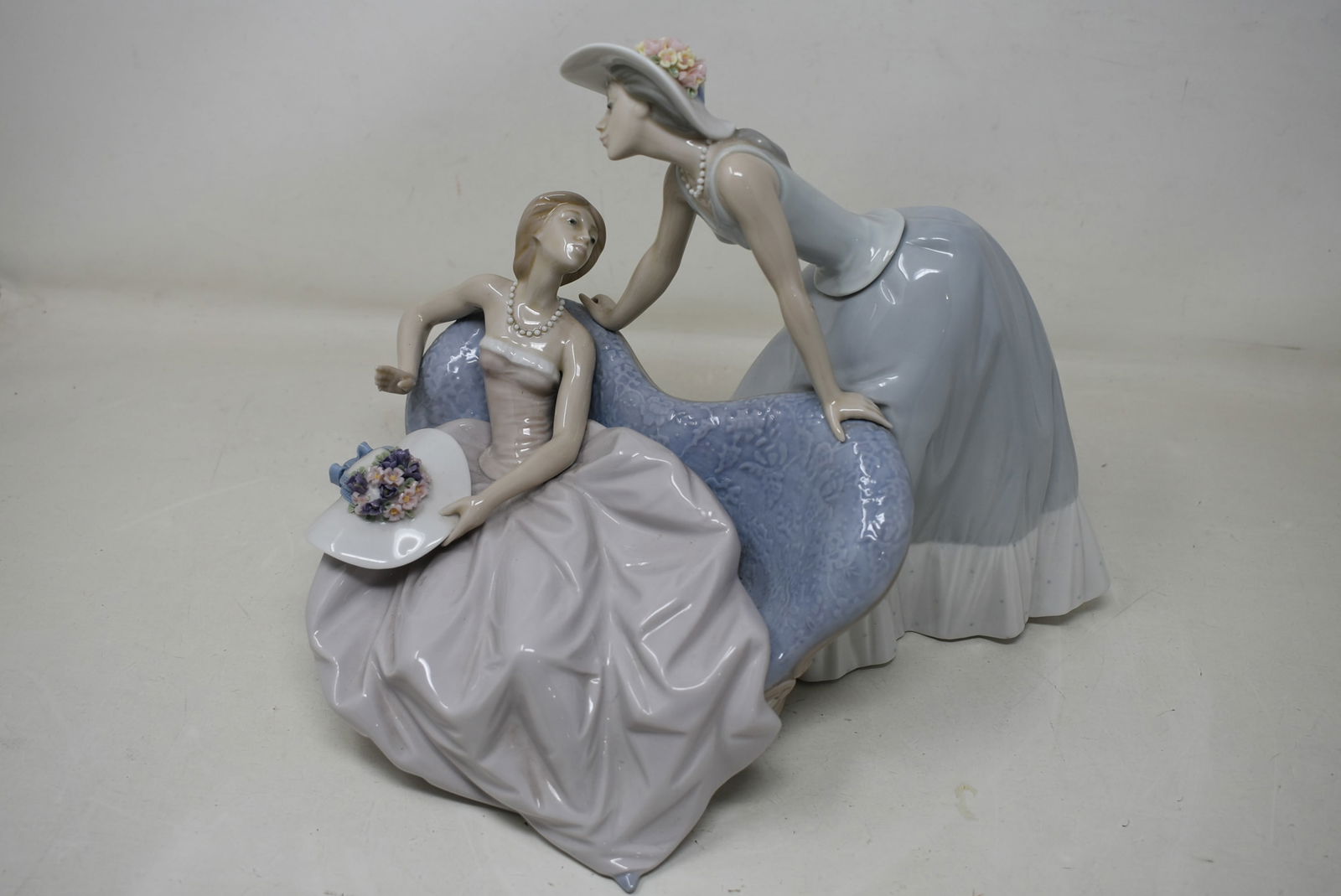 Lladro "Debutante" 5486 Porcelain Figure: Lladro "Debutante" 5486 Figure Porcelain. There is a flower missing from the seated girl's hat, otherwise in good condition. Includes box (box has wear).