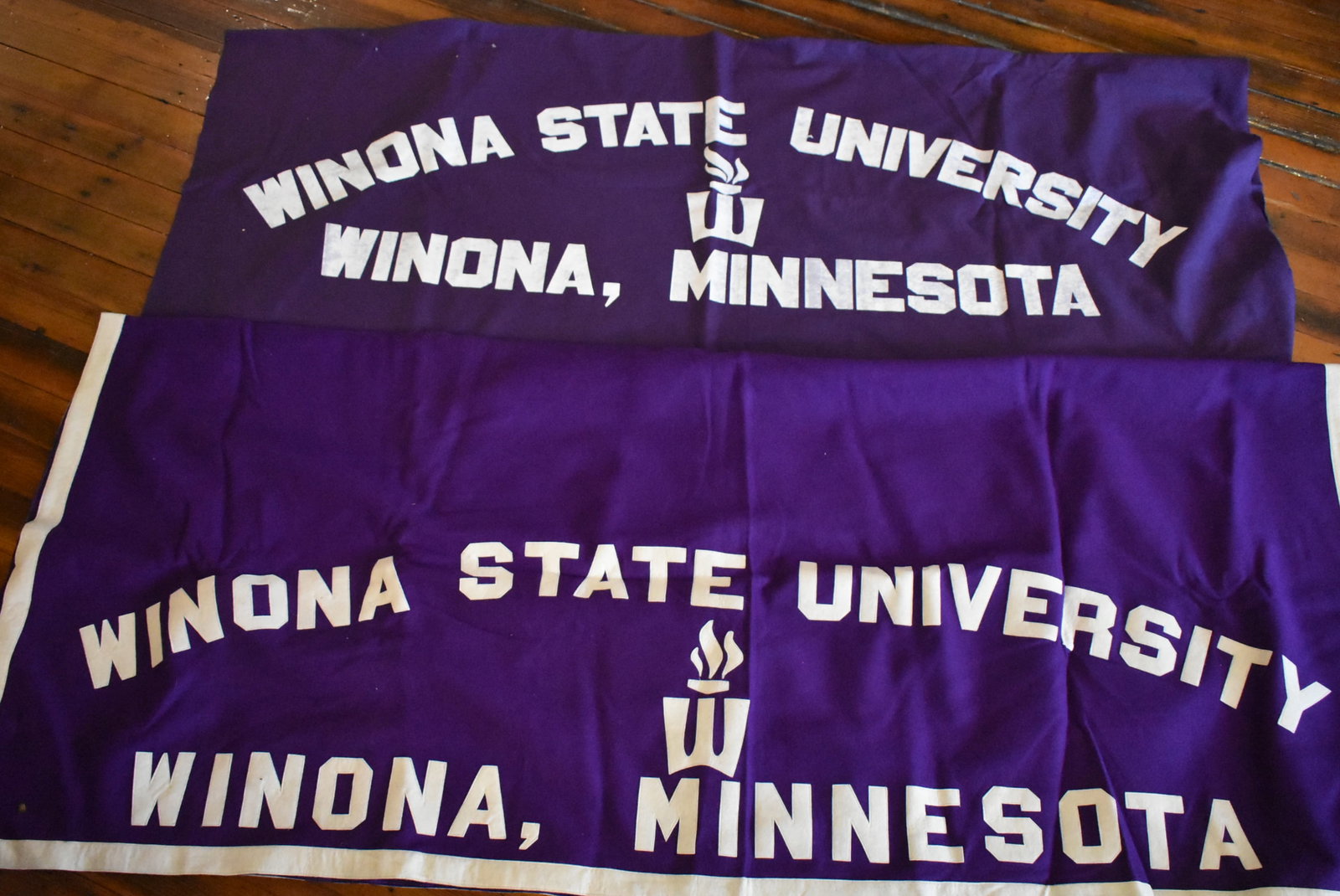 2 Vintage Winona State University Felt Blankets: Lot of 2 Vintage Winona State University Minnesota Purple Felt Blankets. The stitched blanket measures 78"x68" and the transfer blanket measures 74"x60". Both are in good condition with no damage.