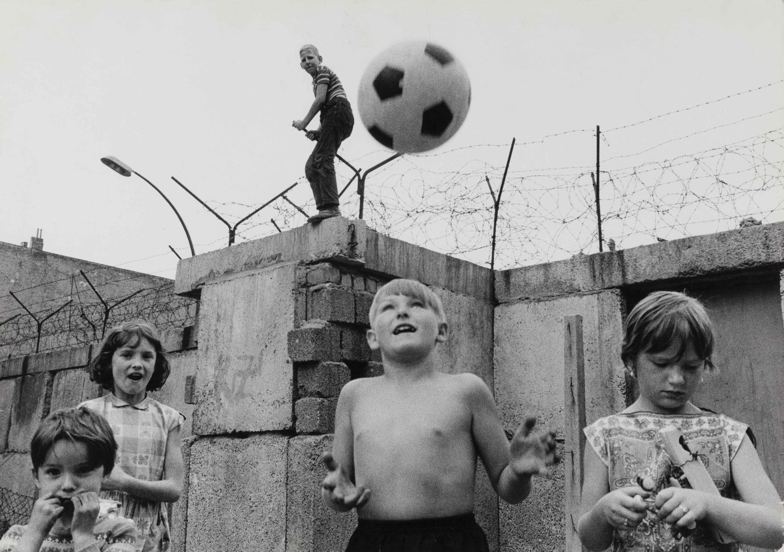 THOMAS HOEPKER (1936–2024): THOMAS HOEPKER (1936–2024) | Children playing in front of the Berlin Wall, 1963 Image Size: 27.3 x 38.8 cm English Vintage gelatin silver print on Agfa paper, in very good condition. Photographe