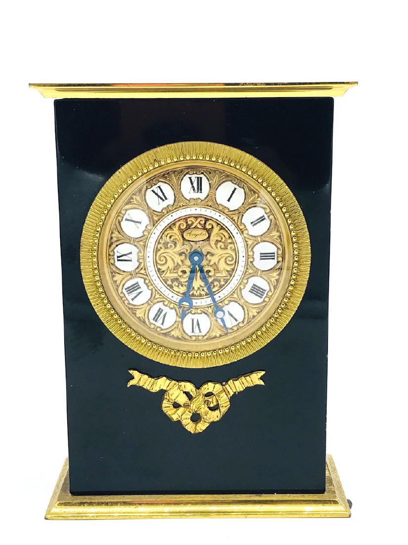 Angelus Black, Gold Porcelain French Clock, Swiss Made: Black Enamel, Gold Porcelain French Clock 6.75 x 5 inches wide. Circa 1950's. Porcelain white colored roman numerals. Gold brass base with black plastic covered body. Swiss marking. Angelus Company