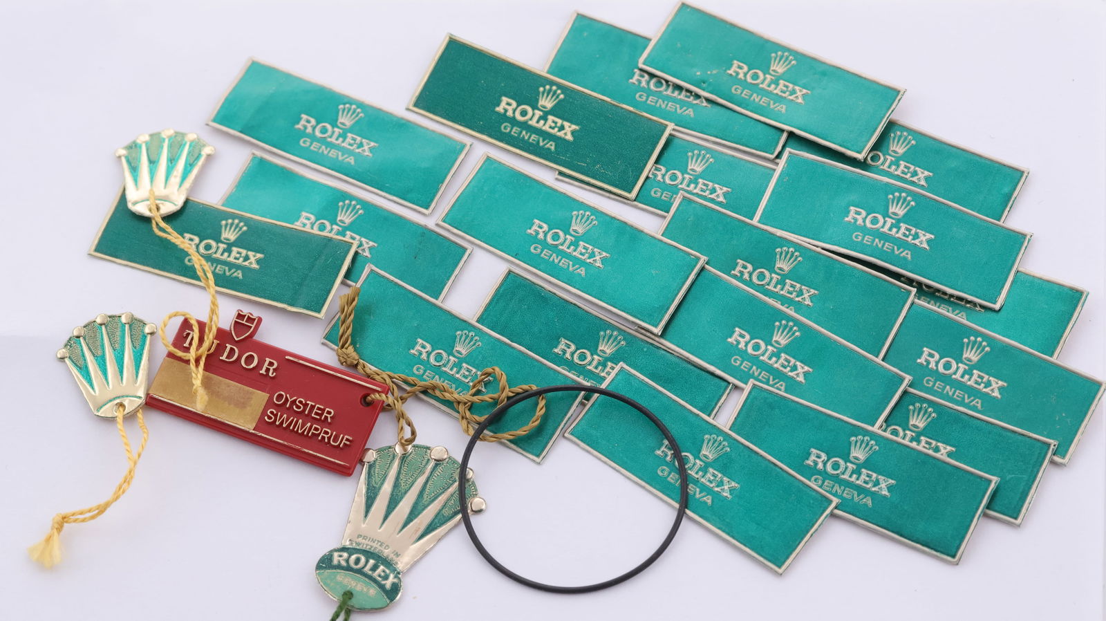 A selection of 22x Rolex tags / plates + 1x Tudor swing tag, including vintage Rolex geneve green: A selection of 22x Rolex tags / plates + 1x Tudor swing tag, including vintage Rolex geneve green tabs, 3x vintage Rolex coronet swing tags, 1x tudor oyster swimpruf red swing tag