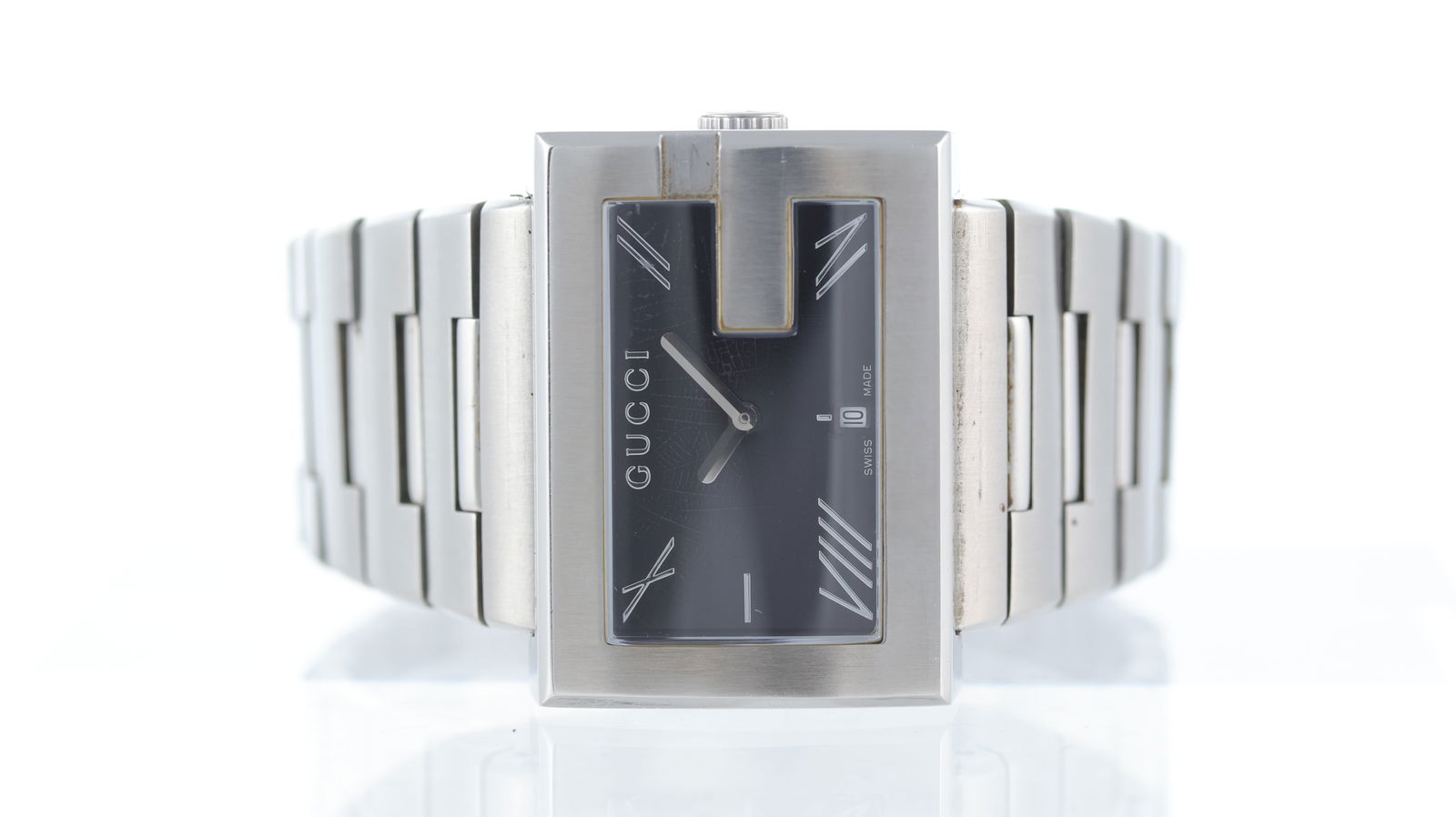 Gucci G Ref 100M: Brand: Gucci Model Name: G Reference: 100M Movement type: Quartz Dial shape: Rectangular Dial colour: Black Dial features: Silver hands and roman numeral hour markers. Date aperture at 6