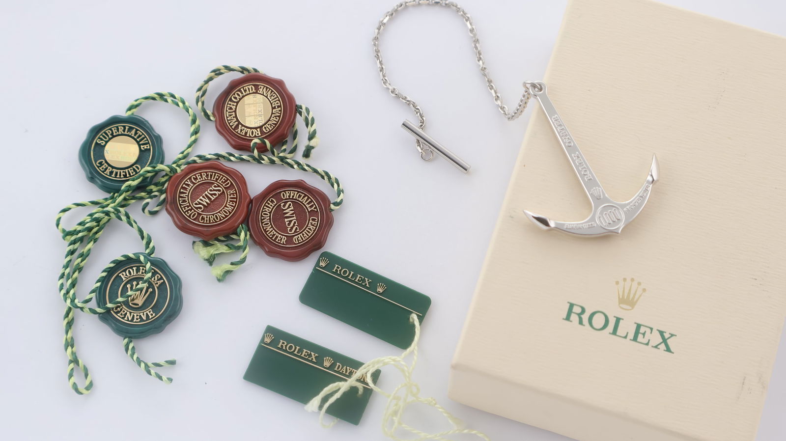 Rolex Swing Tags & Anchor: 1 x small cream Rolex box, 3 red chronometer certified tags, 2 green superlative chronometer tags, 1 green plastic swing tag, 1 green plastic Daytona swing tag, 1 anchor.