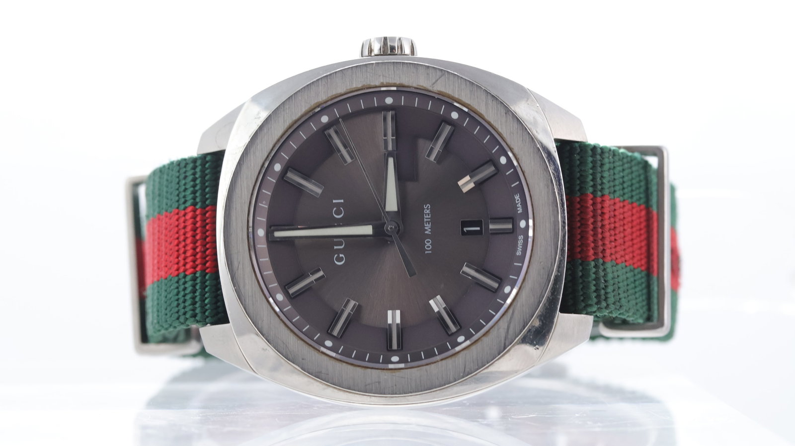 Gucci G Timeless Ref 142.3: Brand: Gucci Model Name: G Timeless Reference: 142.3 Movement type: Quartz Dial shape: Circular Dial colour: Grey Dial features: Silver hands and baton hour markers. Date apert