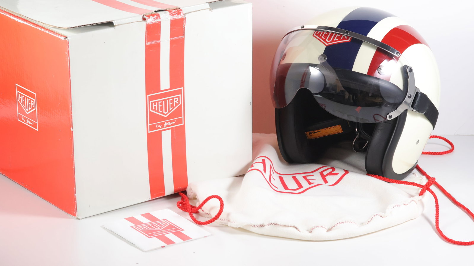 Heuer 1970s Style Racing Jet Helmet - Cream, Blue & Red: A striking modern interpretation of the iconic 1970s racing jet helmet, drawing on Heuer’s rich motorsport heritage and unmistakable period aesthetic. The outer shell is formed from modern fibreglas