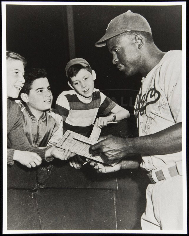 Jackie Robinson Signed Photograph: Title: Signed photograph Author: Robinson, Jackie Description: 10x8" black & white photograph, signed at right.Photograph of Robinson, in uniform, giving his autograph to three young boys. Heading: Pl