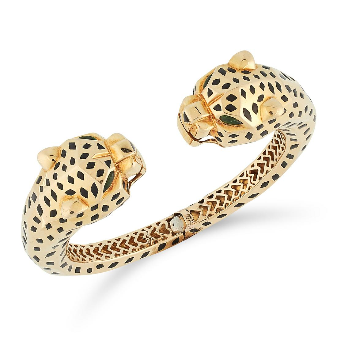 AN ENAMEL AND TOURMALINE DOUBLE PANTHER BANGLE in the: AN ENAMEL AND TOURMALINE DOUBLE PANTHER BANGLE in the style of Cartier Panthere, in the form of two panthers heads set with black enamel and cabochon tourmaline eyes, tests as 18ct yellow gold, unmark