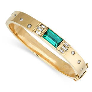 A GREEN TOURMALINE AND DIAMOND BANGLE in yellow gold, the hinged body set with a baguette cut green: A GREEN TOURMALINE AND DIAMOND BANGLE in yellow gold, the hinged body set with a baguette cut green tourmaline of 5.28 carats, accented by baguette cut and round cut diamonds, no assay marks, inner