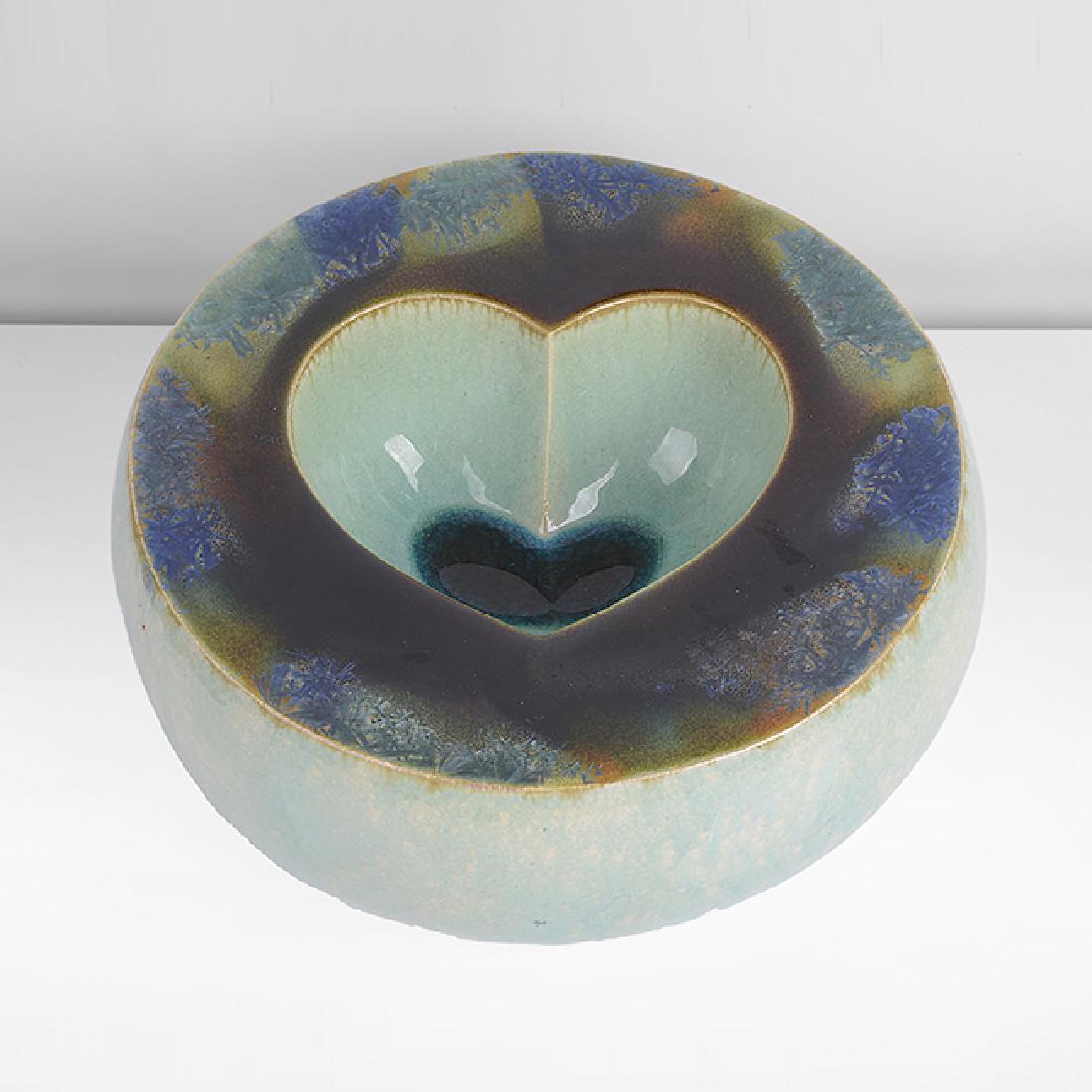 Kate Malone (British, b.1959): Sliced Heart Pillow, 2002 Stoneware, double walled vessel with heart shaped well, mottled shiny green glaze to exterior, glassy blue glaze in the well, the flattened rim with blue and green crystallin