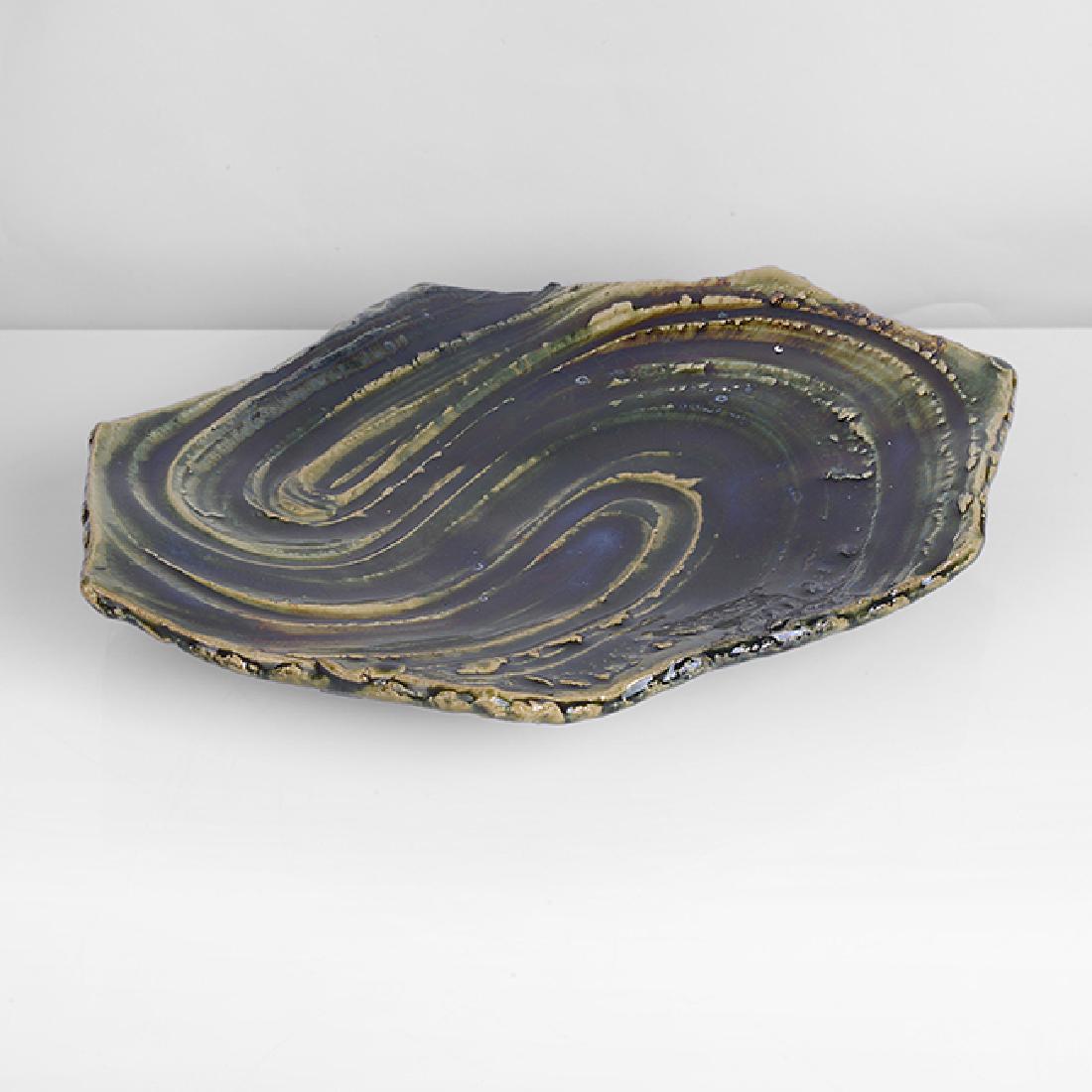 Kato Yasukage (Japanese, b.1964): Oribe Platter Stoneware, deep green, blue and brown oribe glazes over a combed swirling textured surface, angular cut sides, raised on three feet, together with a signed wooden Box H 5.8cm, W 33.1cm,
