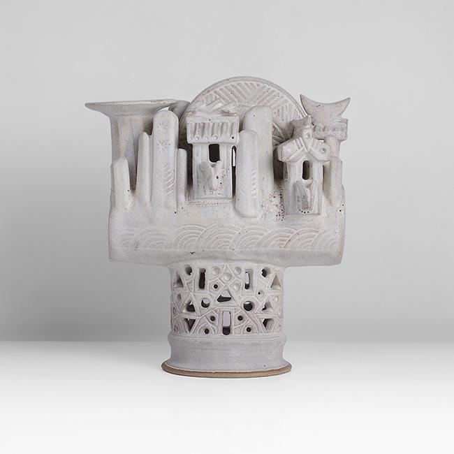 Ian Godfrey (British, 1942-1992): Large Barrel Pot with Landscape, circa 1975 Stoneware, matt white glaze, the barrel form with intricate carved designs, applied with animals, birds, huts, tower, and crescent forms, raised on a tall o