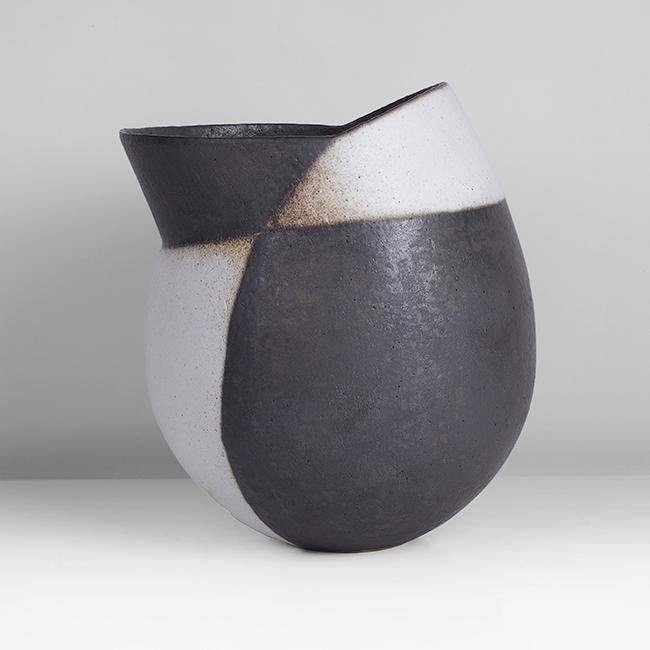 John Ward (British, b.1938): Assymmetric Leaning Vessel, circa 1992 Stoneware, matt black and white glazes, the asymmetric rim cut and angled to one side, impressed JW seal H 23.1cm, W 20.8cm, D 19.0cm PROVENANCE: Private Collect