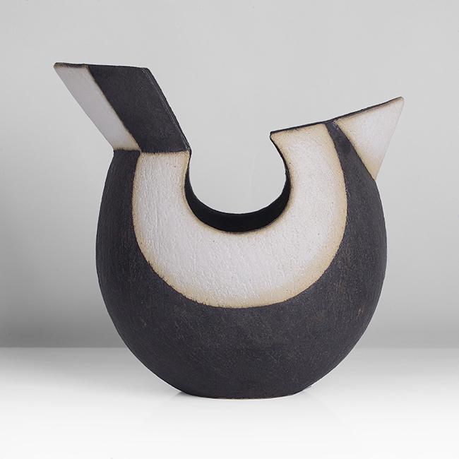 John Ward (British, b.1938): Bird' Vessel, circa 1992 Stoneware, matt black and white glazes over a lightly textured surface, the concentric ring forms following the line of a cut out to the rim on each face, set with a small tri