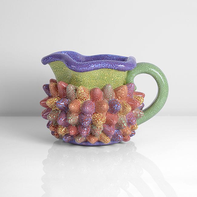 Kate Malone (British, b.1959): Tutti Frutti Bumper Car' Jug, circa 1995 Earthenware, vivid crackle glazes in green, purple and yellow with a multicoloured spiked body, incised signature Size H 18.8cm, W 26.2cm, D 20.1cm Notes PRO