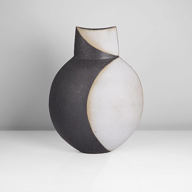 John Ward (British, b. 1938): Disk Pot, circa 1990 Stoneware, matt black and white curved forms front and back over a lightly textured surface, the flattened rounded form with short tapering neck and dipped rim, impressed J