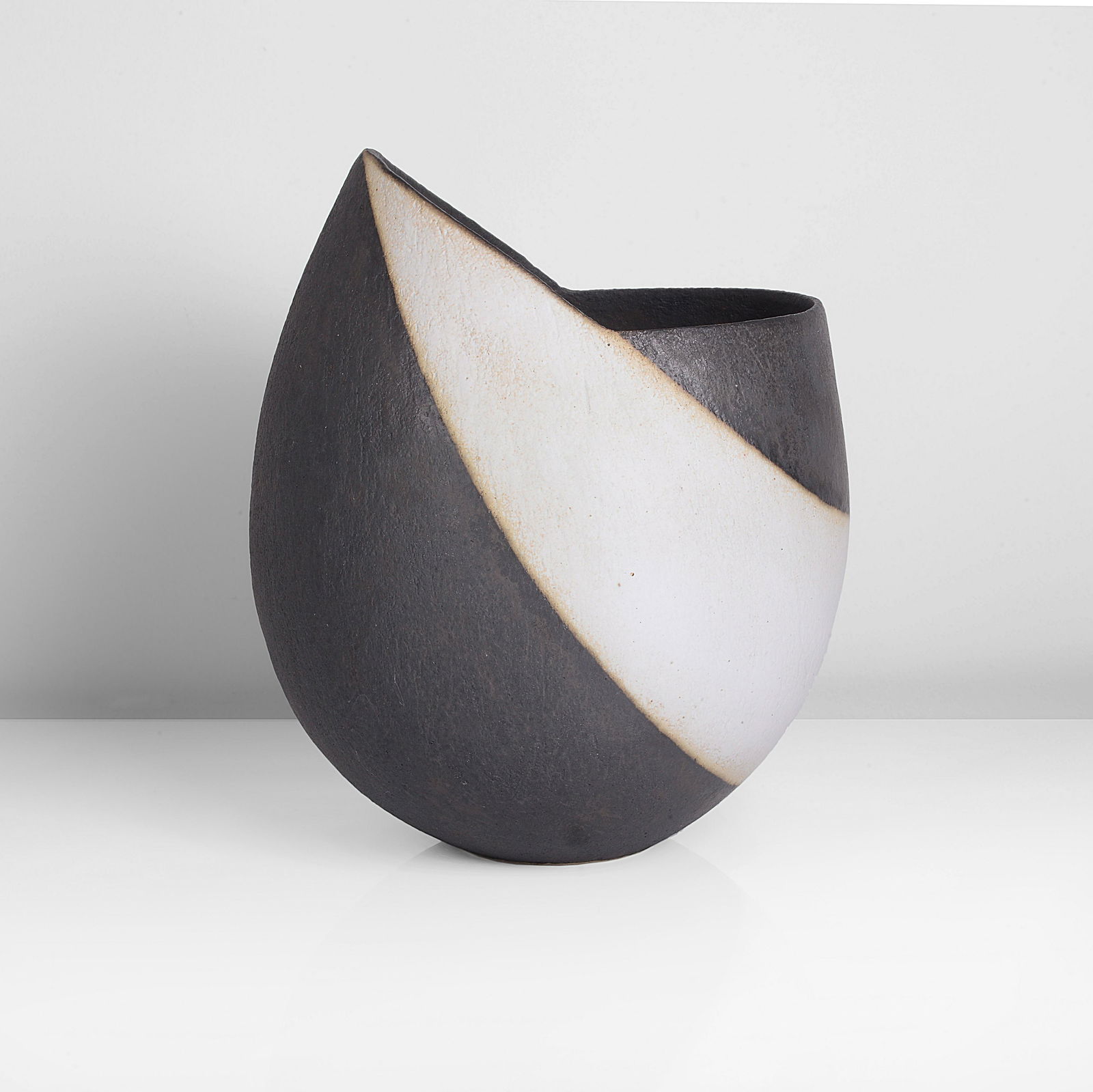 John Ward (British, b. 1938): Vessel with Pointed Rim, circa 1990 Stoneware, matt black and white glazes over a lightly textured surface, the rim rising to a single point on one side with an angled ridge running down from the poin