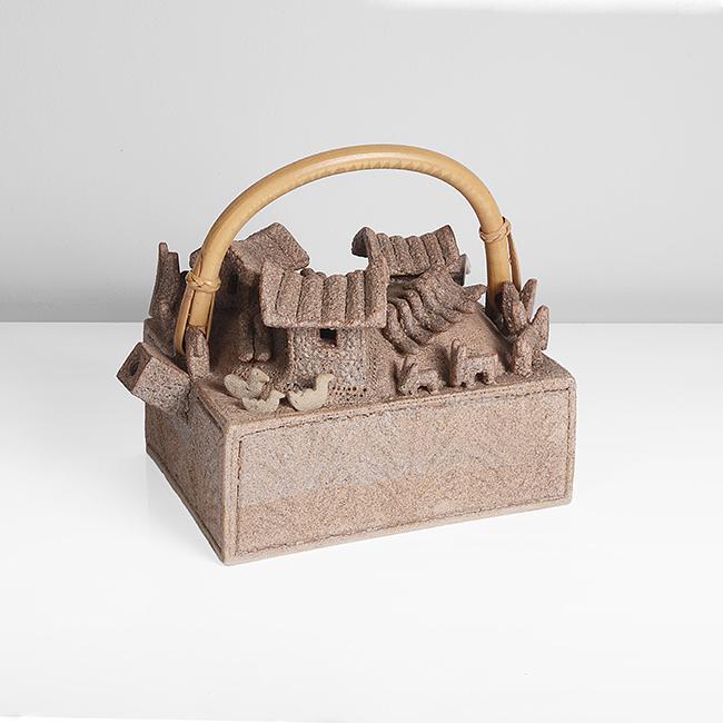 Ian Godfrey (British, 1942-1992): Village Teapot, circa 1974 Stoneware, dry brown and grey glazes, mounted with huts, birds, beasts and a boat, of which three birds, a hut and the boat are detachable, the rectangular form with carved
