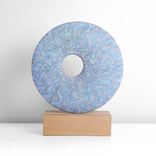 Peter Beard (British, b.1951): Disc' Form Stoneware, alternating undulating bands in blue and grey glazes to the front, the reverse with mottled blue and grey glazes and impressed shell marks from the firing, the ring form mounted