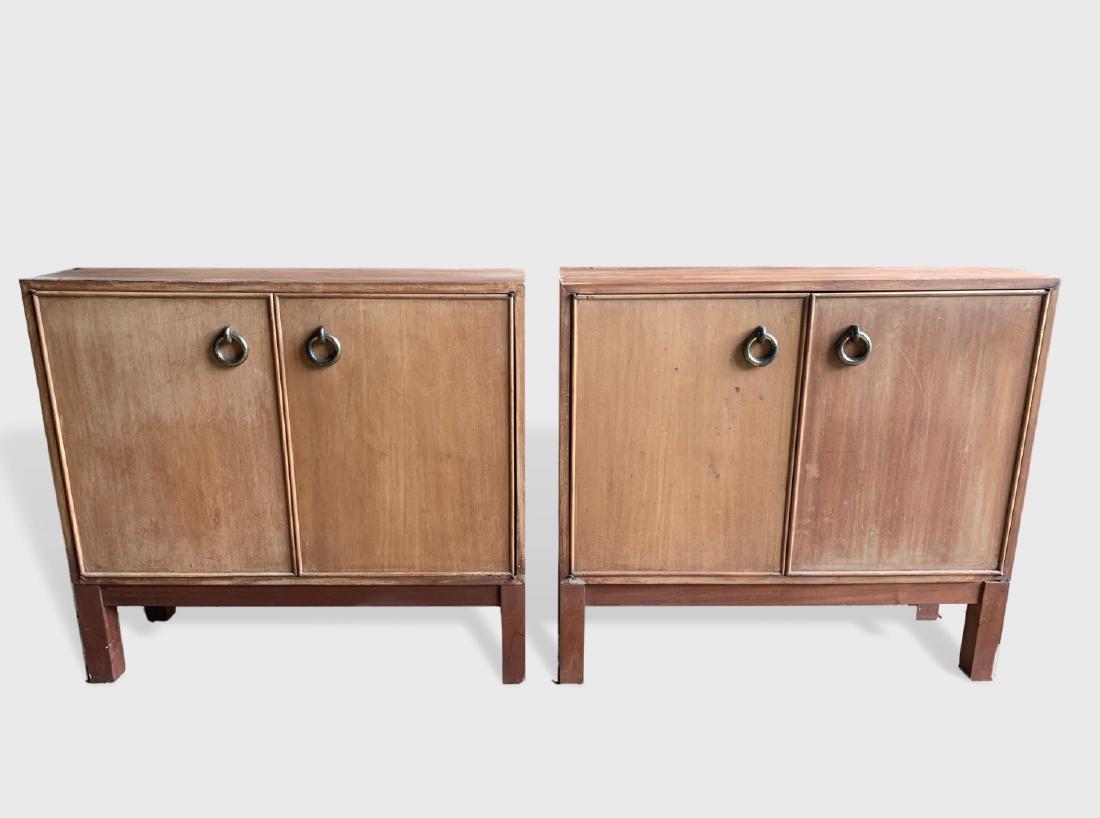 Pair Of 2-Door Cabinets: A pair of 2 door cabinets in the style of Jacques Adnet, in light mahogany veneer, on simple wood bases, brass ring handles, circa 1950. Dimensions: 36" w x 12" d x 33" h. Need restoration, chips to v