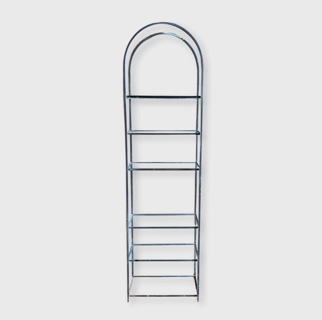 Iron And Glass Etegere: An arch top iron and glass etegere with 6 shelves, circa 1950. Dimensions: 21" w x 12" d x 79" h One glass shelf missing, chips to glass shelves.