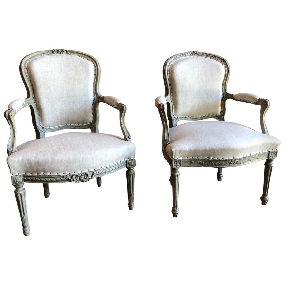 Matched Pair of Louis XVI Armchairs, 1780s: A matched companion pair of transitional Louis XVI period fauteuils in old grey painted finish, the arms showing elements of the earlier Louis XV period with subtle curves and scrolls, the back and se