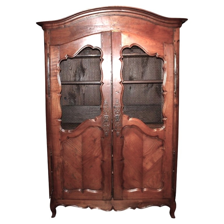 French Louis XV Bookcase, Cherry: A French Louis XV period biblioteque in cherrywood, circa 1780, with arched cornice, wire grill doors, interior adjustable selves on cabriole legs. Working lock and key. 21.5" d x 58" w x 84" h