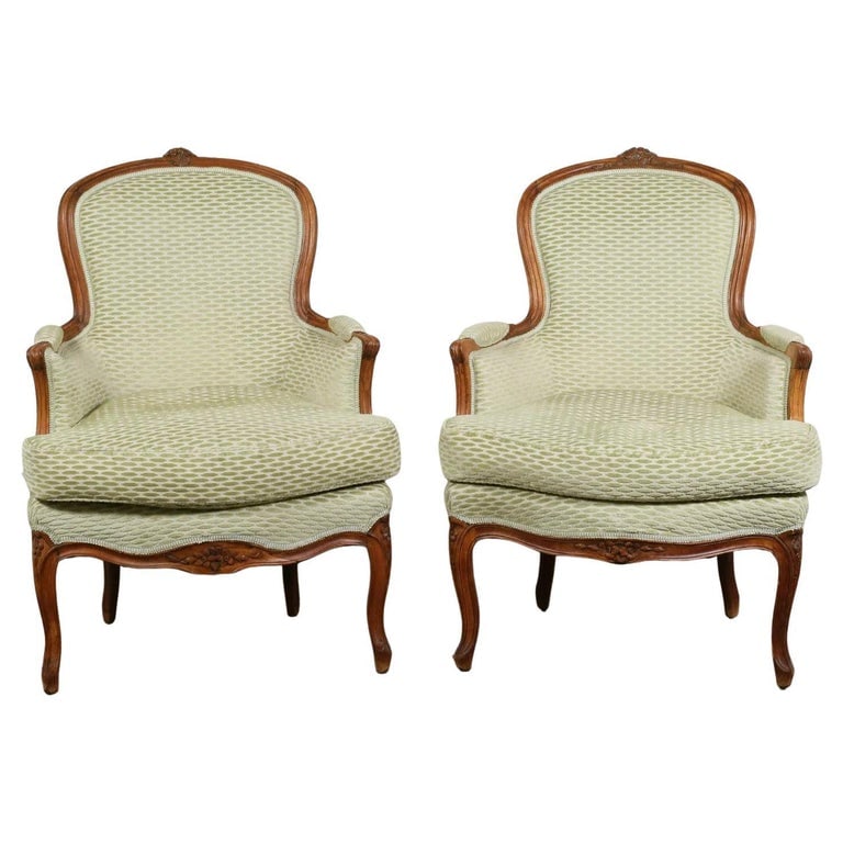Pair of French Louis XV Style Bergeres: A pair of French Louis XV style bergères in beech, upholstered in light green fabric with loose seat cushions, the top and bottom rails carved with floral decoration. 19th century. 26" w x 27" d x 37