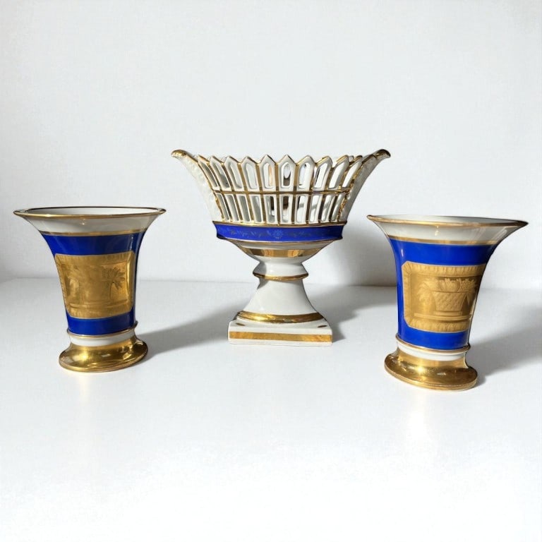 Old Paris Porcelain Garniture Set: A set of 3 pieces of Old Paris porcelain, including a pair of vases decorated with musical themes and a pieced basket on base, early 19th century. 4" d x 8" w x 6.5" h largest.