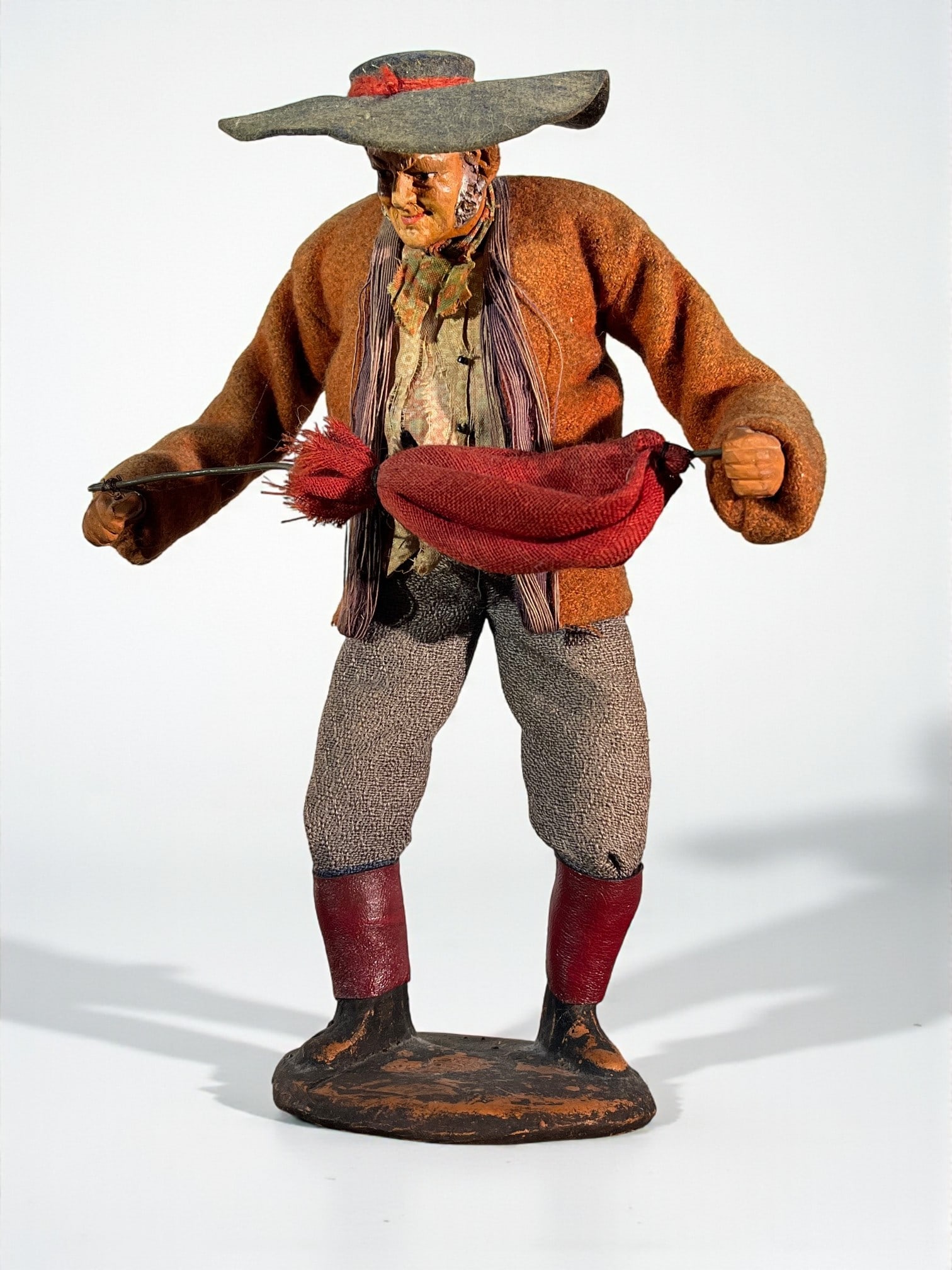 Neopolitan Creche Figure: A Neopolitan creche figure or santon doll, in terracotta and antique cloth, early 20th century depicting a man with an umbrella, signed by Jonglas. 3" d x 6" w x 11" h