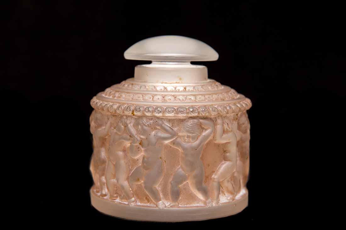 Lalique Dancing Nude Cupids Perfume: Lalique "Dancing Nude Cupids" perfume bottle with stopper in clear and frosted glass with brown tint, signed Lalique Paris on base France, 20th c 4.5"H x 3.5" diameter Condition: Very good
