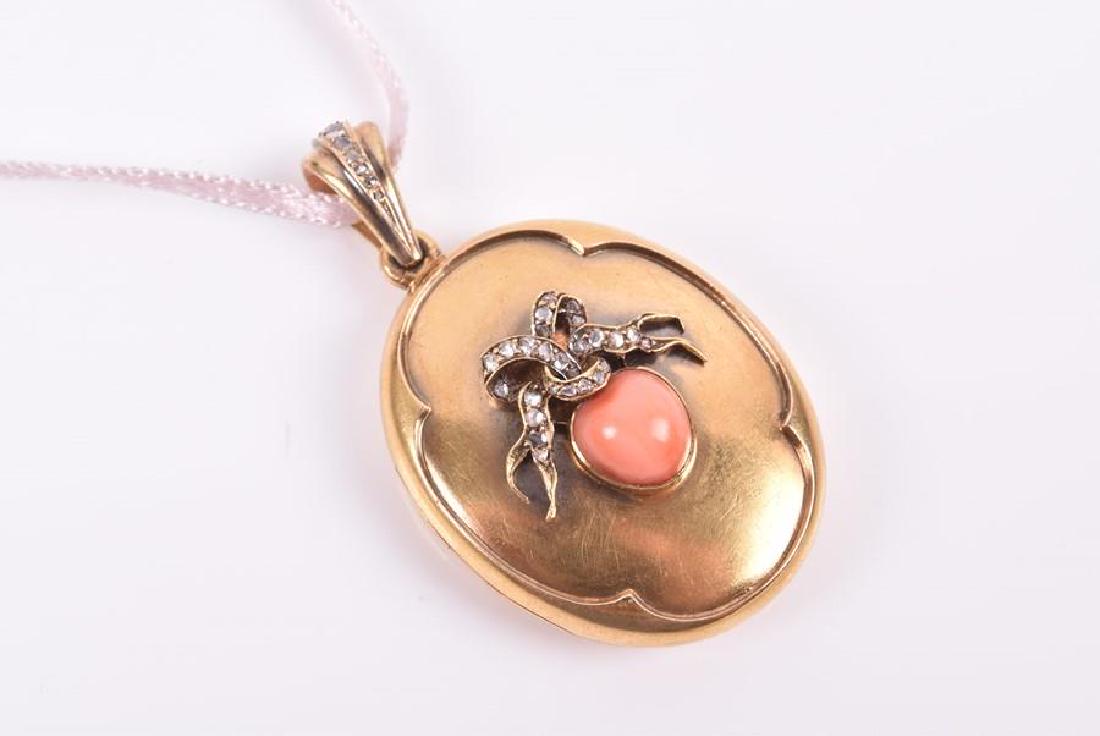 A yellow gold, diamond, and coral locket pendant of: A yellow gold, diamond, and coral locket pendant of oval form, inset with a piece of peach-coloured coral, beneath an applied ribbon-twist mount inset with rose-cut diamonds, opening to reveal double
