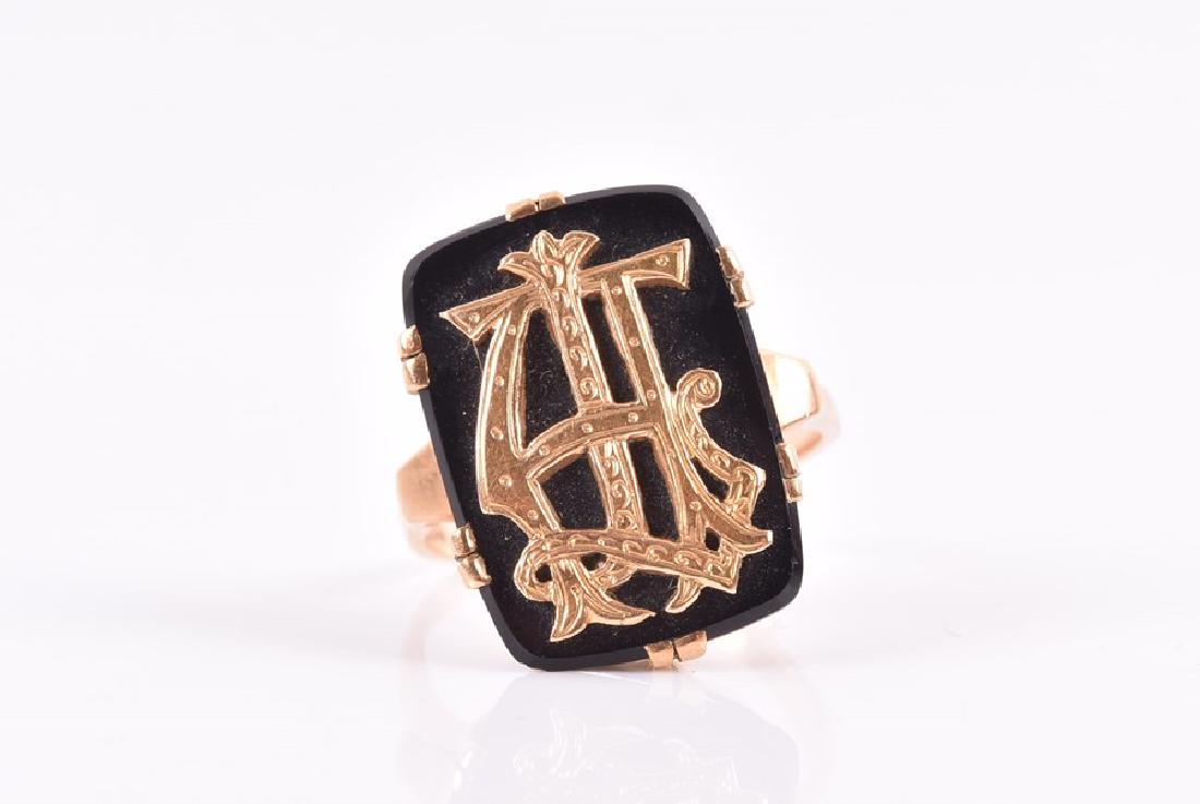 An 18ct yellow gold and onyx ring with applied gold: An 18ct yellow gold and onyx ring with applied gold initials to onyx plaque, possibly TH, size N, 5.6 grams.
