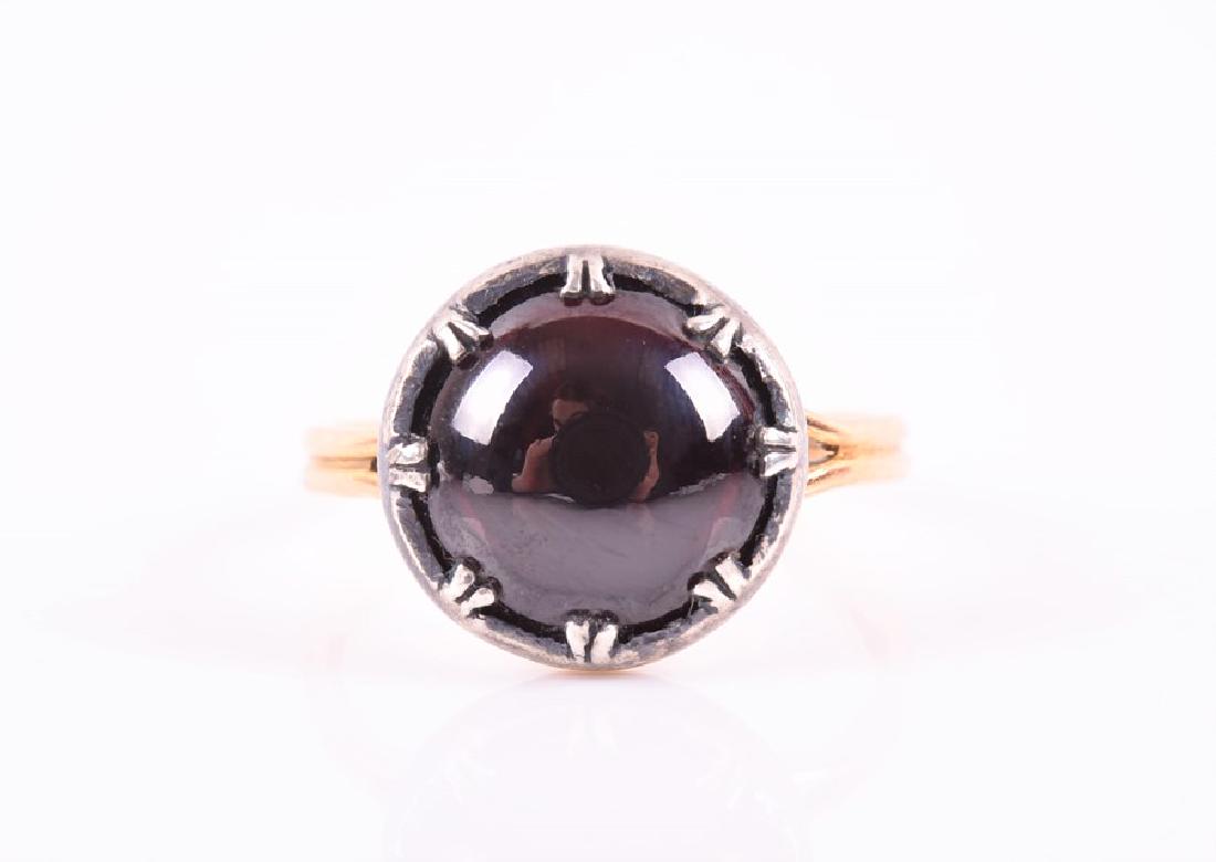 A yellow metal and garnet ring in the antique style,: A yellow metal and garnet ring in the antique style, set with a round cabochon garnet, claw-set in silver, with yellow metal shank (tests as gold), garnet approximately 11mm diameter, size M 1/2, 3.8 