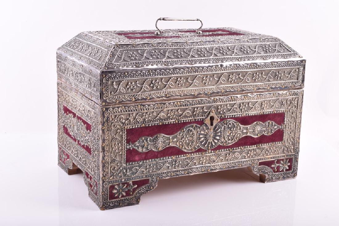A mid 19th century colonial Spanish jewel box cased in: A mid 19th century colonial Spanish jewel box cased in heavily decorated silver with flashes of velvet, the box opening to reveal a part silk lined interior and mirror. 18 cm x 28 cm x 16.5 cm.