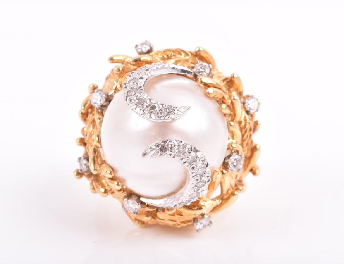 In the style of Grima. An 18ct yellow gold, diamond,: In the style of Grima. An 18ct yellow gold, diamond, and pearl cocktail ring the raised mount set with a white mabe pearl, surmounted with two white gold and diamond swirls, within a stylised nest of