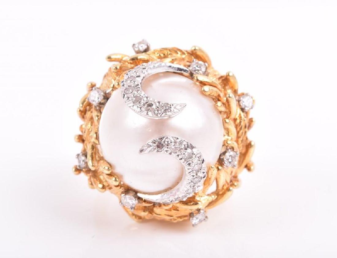 In the style of Grima. An 18ct yellow gold, diamond,: In the style of Grima. An 18ct yellow gold, diamond, and pearl cocktail ring the raised mount set with a white mabe pearl, surmounted with two white gold and diamond swirls, within a stylised nest of